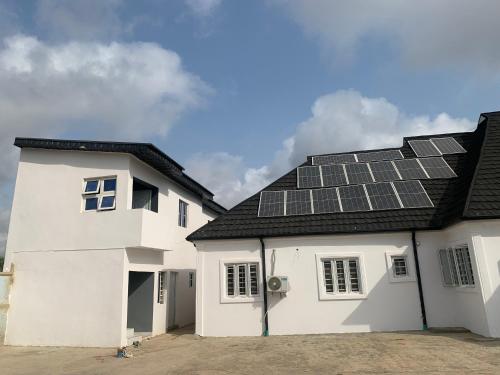 a white house with solar panels on the roof at Umbrella Properties hotels and apartments - Moniya in Ibadan