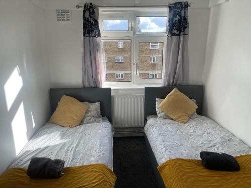 two beds in a room with a window at London Budget Maisonette in London