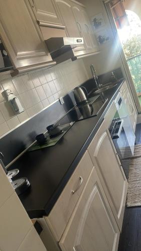 une cuisine avec des armoires blanches et un comptoir noir dans l'établissement Apartment near Beach-Airport Open 24h, à Saint-Laurent-du-Var