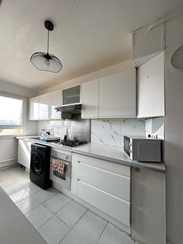 Il comprend une cuisine blanche équipée d'une cuisinière et d'un four micro-ondes. dans l'établissement Mantes-la-Jolie Apartment 8p, à Mantes-la-Jolie