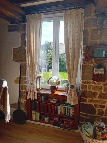 a window with curtains and a book shelf with books at La Jolie Petite Maison for groups 1-5 in Fontenermont