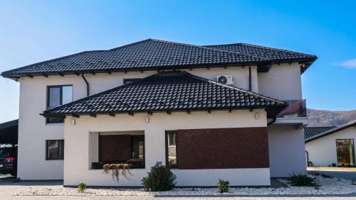 a white house with a black roof at Casa Ambientt in Curtea de Argeş