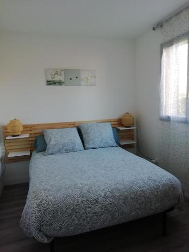 une chambre avec un lit avec des draps bleus et une fenêtre dans l'établissement Maison entre Seine et forêt, à Aizier