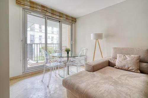 un salon avec un canapé, une table et une fenêtre dans l'établissement Spacious & Cozy Apartment - Trocadero Passy, à Paris