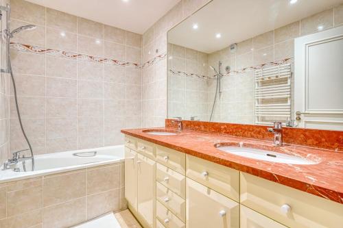 une salle de bain avec deux lavabos, une baignoire et une douche dans l'établissement Spacious & Cozy Apartment - Trocadero Passy, à Paris