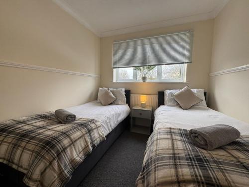 two beds in a small room with a window at Olive House Long Stays Sleeps 8 Free Parking in Swindon