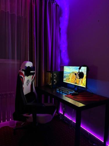 a desk with a computer and a chair with purple lights at Harmony Inn in Almaty