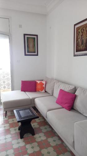 a living room with a white couch with pink pillows at Appartement vue sur mer à Mahdia in Mahdia
