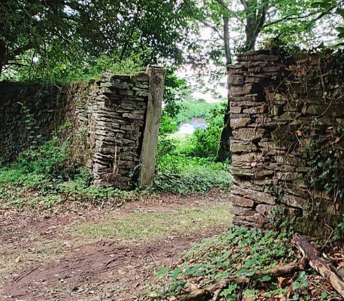an old stone wall with a wooden door in a field at Camping Vieilles Charrues Petit-déjeuner navette et priscine inclus dans le prix proche Carhaix in Motreff