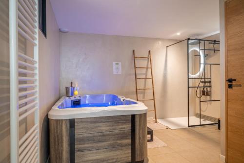 a bathroom with a blue tub and a shower at La Grange Clyna - Love Room in Parigné-lʼÉvêque