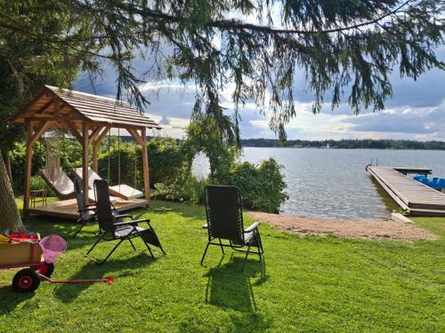 two chairs and a gazebo next to a lake at Widokówka 13 in Mikołajki