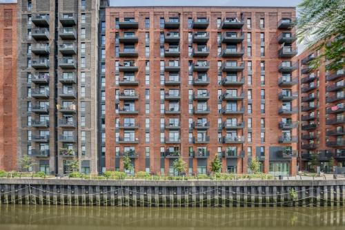 a tall apartment building next to a body of water at Modern, Spacious 2bed, 2bath apartment in Barking in Barking