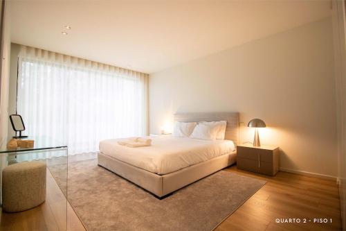 a bedroom with a white bed and a large window at Villa with Pool Casa Sol Poente by casaporto207 in Vila Verde
