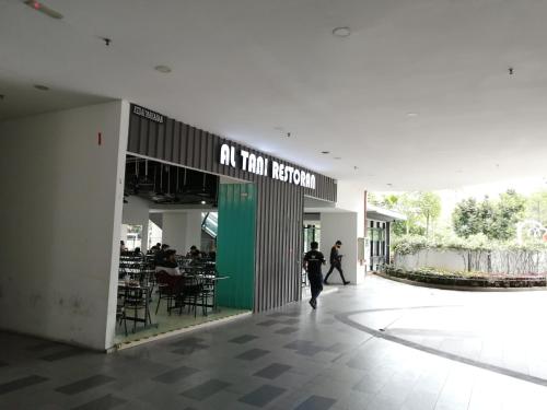 a person walking through a building with a restaurant at i-Duplex 1M2R2B Condo - LED Garden, Fun Fair, Waterpark, Wax Museum, Mall & More! in Shah Alam