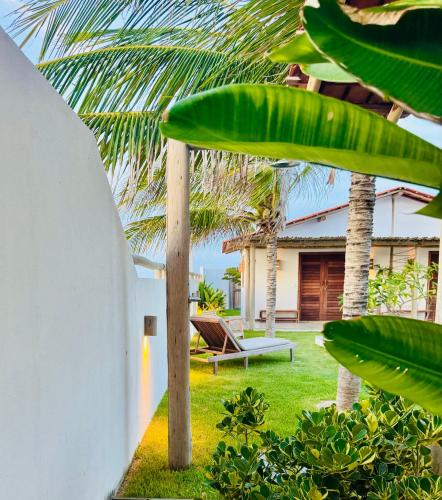 a garden with a bench and a house with palm trees at Casa Calango suites in Fortim