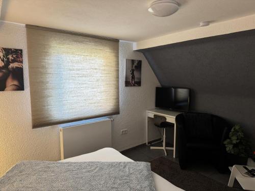 a bedroom with a window with a desk and a television at M & E Ferienwohnung in Bad Mergentheim