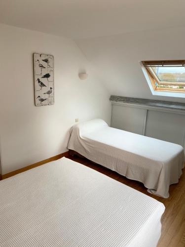 deux lits dans une chambre blanche avec une fenêtre dans l'établissement La Petite Maison, à Port-en-Bessin-Huppain