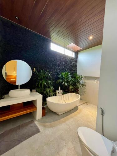a bathroom with a tub and a mirror and plants at Puri Gia in Mambat