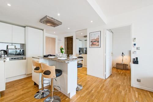 une cuisine avec des placards blancs et un îlot de cuisine dans l'établissement VILLA FLORENTINE III - Somptueux deux pièces MONACO - Vue mer - Parking, à Beausoleil