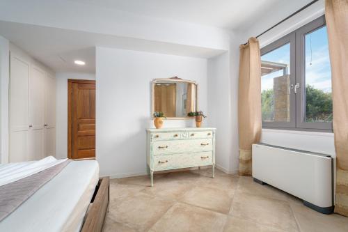 a bedroom with a dresser and a mirror and a window at Mar-A-Poros in Poros
