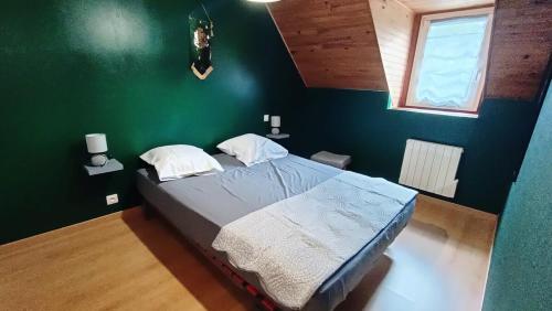 - une chambre dotée d'un lit avec un mur vert dans l'établissement Maison de bourg magique de 1860, à Loguivy-Plougras