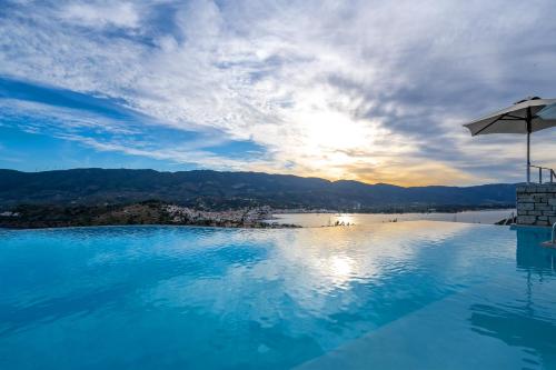 a swimming pool with an umbrella and the sunset at Mar-A-Poros in Poros