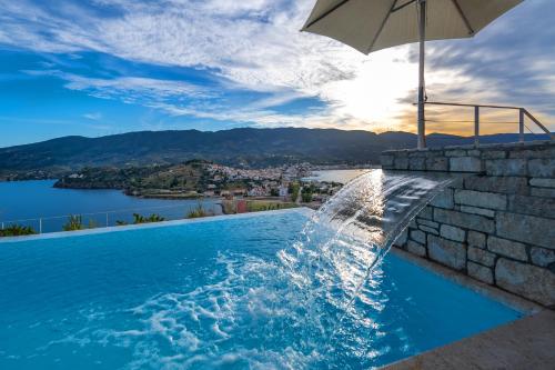 a swimming pool with an umbrella and a water fountain at Mar-A-Poros in Poros
