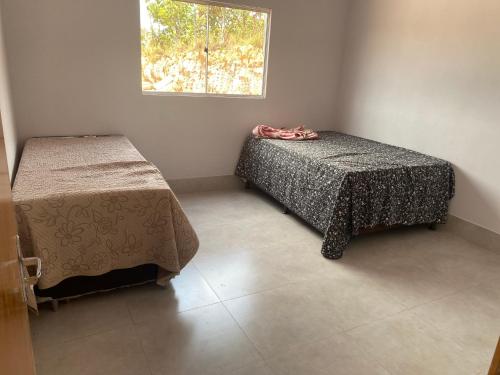 a room with two beds and a window at Condomínio Santa fe in Abadiânia