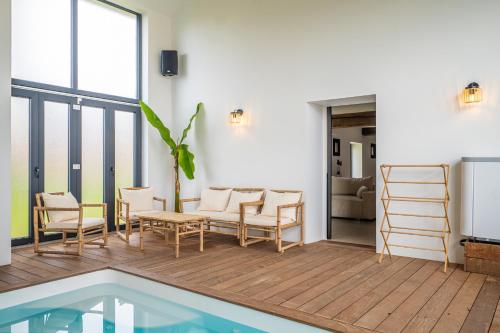 une terrasse avec des chaises, une table et une piscine dans l'établissement Grange de Clyna-Piscine & Spa à 10 min du circuit, à Parigné-lʼÉvêque