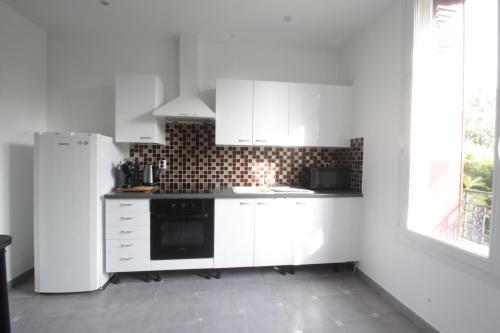 une cuisine blanche avec des armoires blanches et un réfrigérateur dans l'établissement La plaine de Villemoisson, à Villemoisson-sur-Orge
