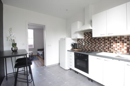 La cuisine est équipée de placards blancs et d'un four avec plaques de cuisson noires. dans l'établissement La plaine de Villemoisson, à Villemoisson-sur-Orge