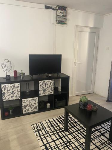 un salon avec une télévision à écran plat sur une étagère dans l'établissement Petit nid au centre historique de Marvejols, à Marvejols