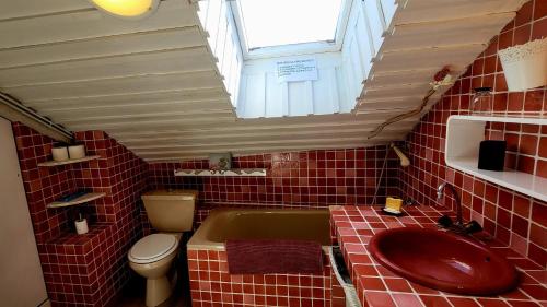 La salle de bains est pourvue de carrelage rouge, d'un lavabo et de toilettes. dans l'établissement Appartement de montagne, CHARME et calme au pied des pistes, à Enchastrayes