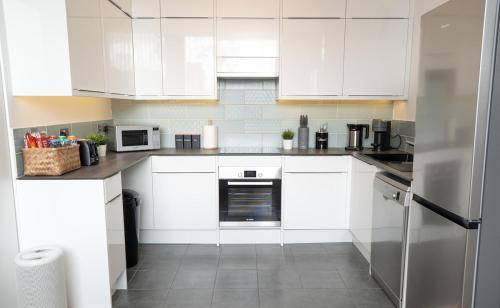 a white kitchen with white cabinets and appliances at Modern 2-Bed Apartment Near ExCeL & O2 - Accommodates up to 4 Guests Max in London
