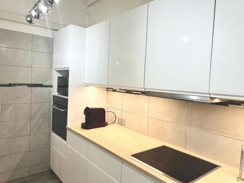 a kitchen with white cabinets and a black bag on the counter at Amiral Courbet Apartment in Juan-les-Pins