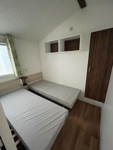 une petite chambre avec deux lits et une fenêtre dans l'établissement Mobile home 6 personnes 1semaine minimum juillet août, à Saint-Hilaire-de-Riez
