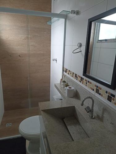 a bathroom with a sink and a toilet and a mirror at Apartamento completo 2 quartos a 3km basílica in Aparecida