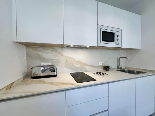 a white kitchen with a sink and a microwave at Hotel Apartamentos Marina Luz in Chipiona