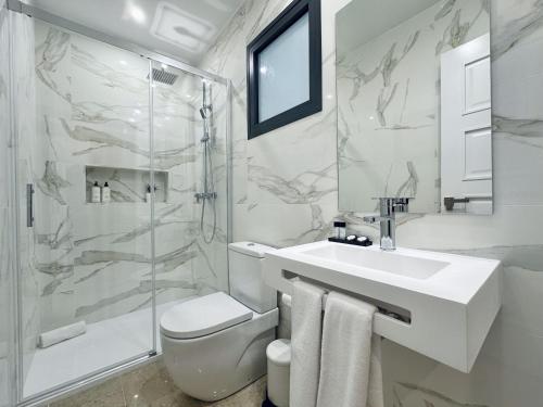 a white bathroom with a sink and a shower at Hotel Apartamentos Marina Luz in Chipiona