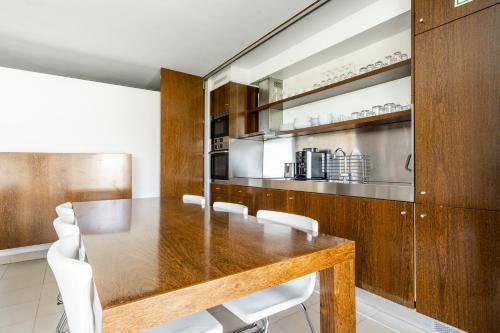 a dining room with a wooden table and white chairs at Apartamento Salgados Beach in Albufeira