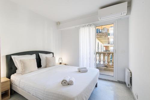 - une chambre blanche avec un grand lit et des serviettes dans l'établissement Le Victoria, élégant T2 au bord des plages, piscine, sauna, à Menton