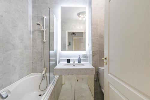 une salle de bain avec un lavabo, une baignoire et des toilettes dans l'établissement Le Victoria, élégant T2 au bord des plages, piscine, sauna, à Menton