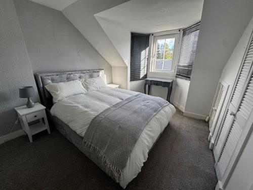 a bedroom with a large bed and two windows at Modern 3-Bedroom Home with Cozy Cinema-Style Living Space in Cumbernauld