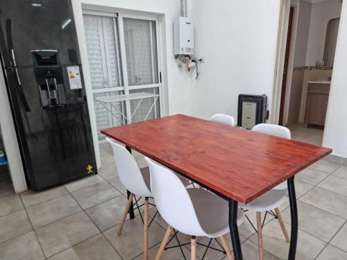 a kitchen with a wooden table and white chairs at Departamento Familiar muy amplio in Concepción del Uruguay