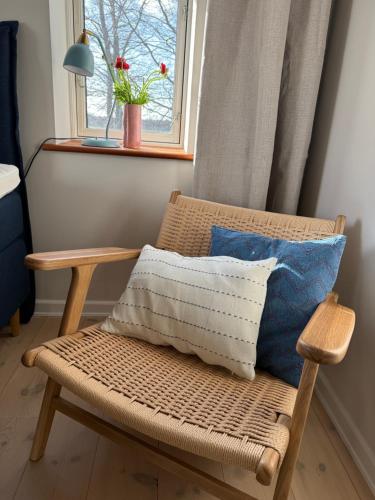 a wicker chair with a pillow and a window at Digebjerggaard Bed & Breakfast in Vester-Skerninge