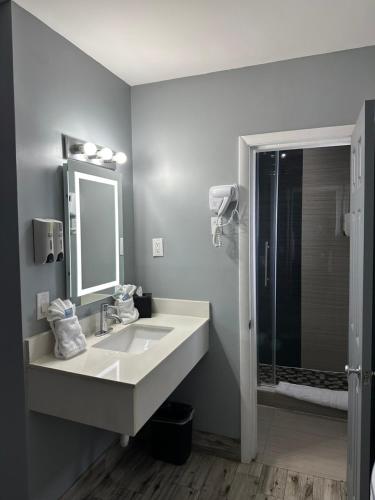 a bathroom with a sink and a mirror and a shower at Historic Waterfront Marion Motor Lodge in downtown St Augustine in Saint Augustine
