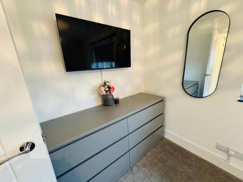 a bathroom with a dresser with a mirror and a tv at Modern Home Basildon Long stay Contractor Sleeps 6 in Basildon