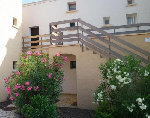 un bâtiment avec un escalier et des fleurs devant lui dans l'établissement la pépite du cap d'agde, au Cap d'Agde