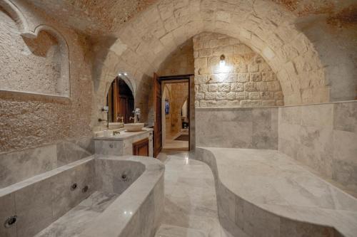a stone bathroom with a tub and a sink at Kemerhan Cave Suites in Urgup