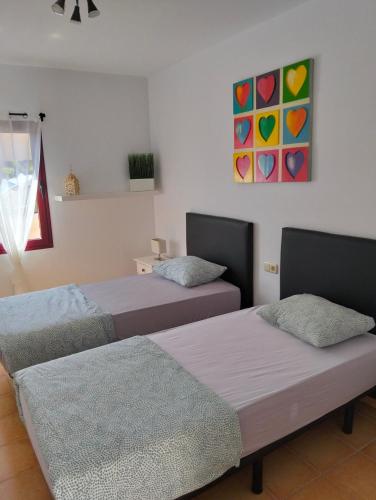 a room with two beds and a painting on the wall at Casa Vacacional Villa Liberty in Corralejo